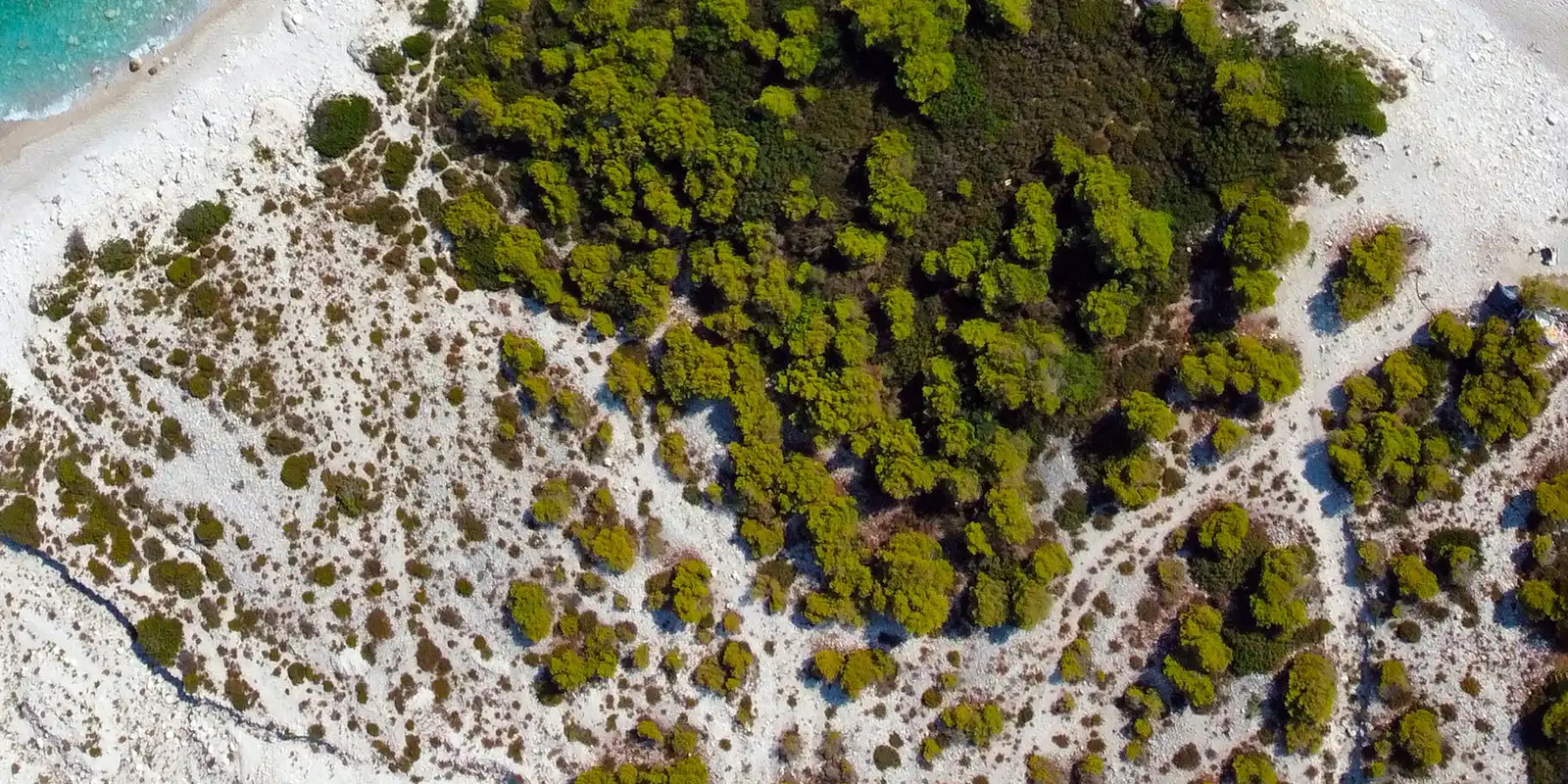 Luftaufnahme eines Sandstrands mit türkisfarbenem Wasser bei Palasë an der albanischen Riviera