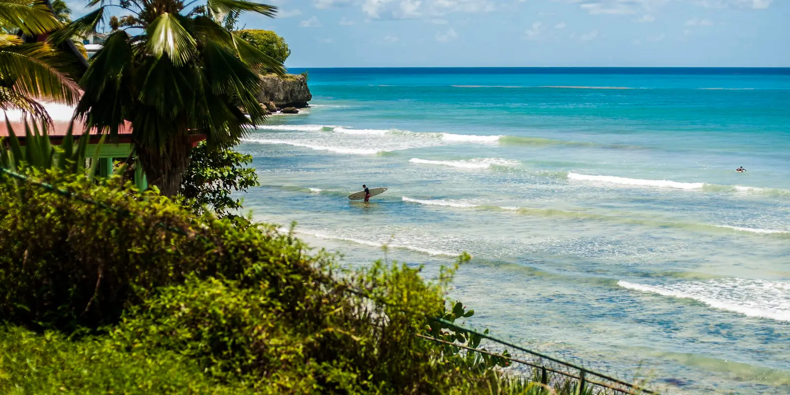 Barbados' wilder Atlantic side draws surfers — coverage here can thin out compared to the resort-heavy west coast Surfer riding a wave off the coast of Barbados