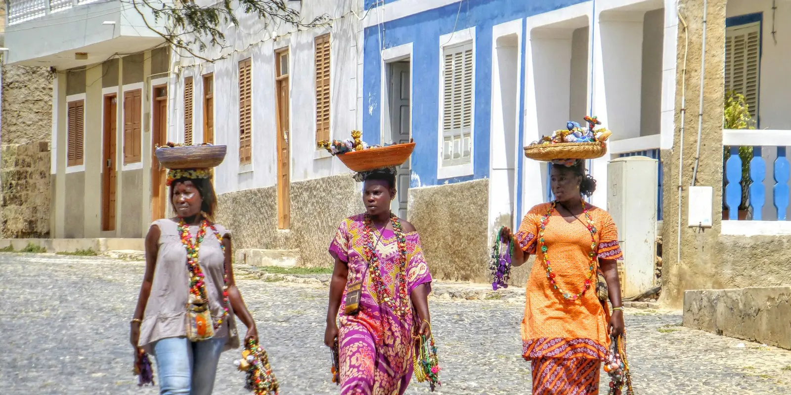 Three women in Cape Verde balancing baskets on their heads in Boa Vista