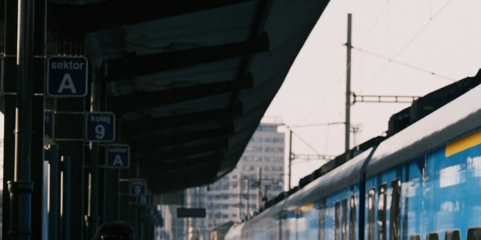 Ein Reisender mit Rucksack auf dem Bahnsteig eines europäischen Bahnhofs