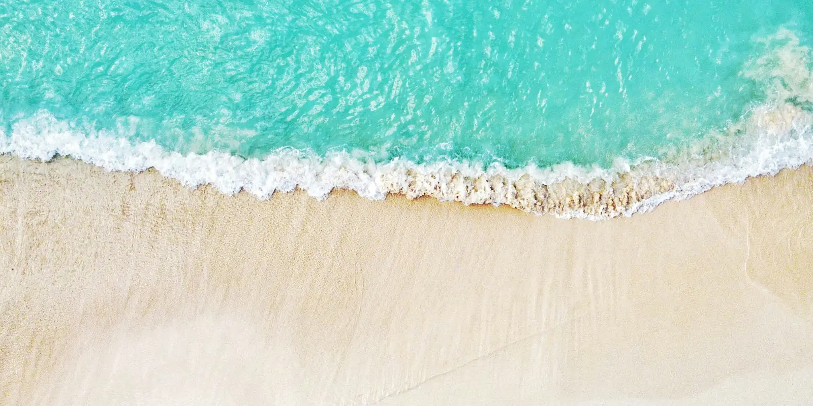 Aerial view of a white sand beach and turquoise water in the Cayman Islands