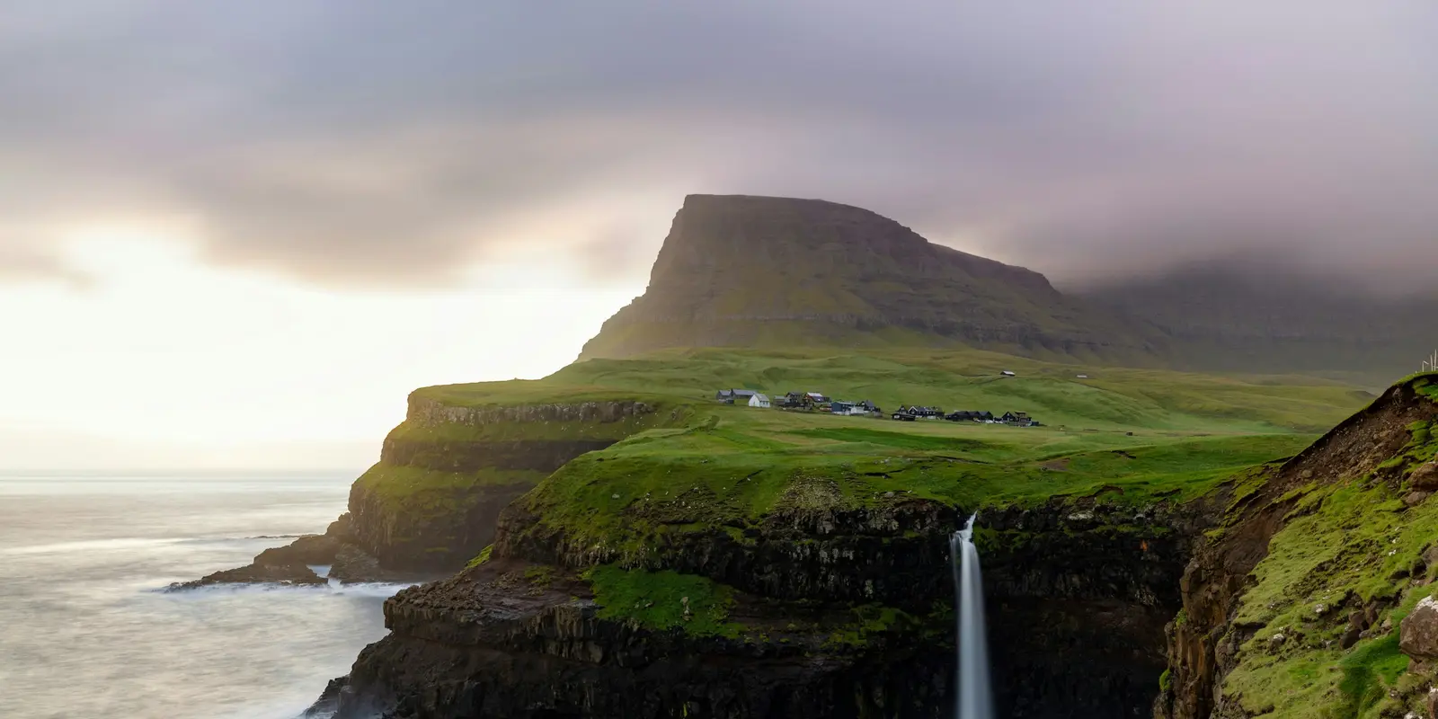 Múlafossur waterfall cascading off a cliff into the ocean near Gásadalur, Faroe Islands