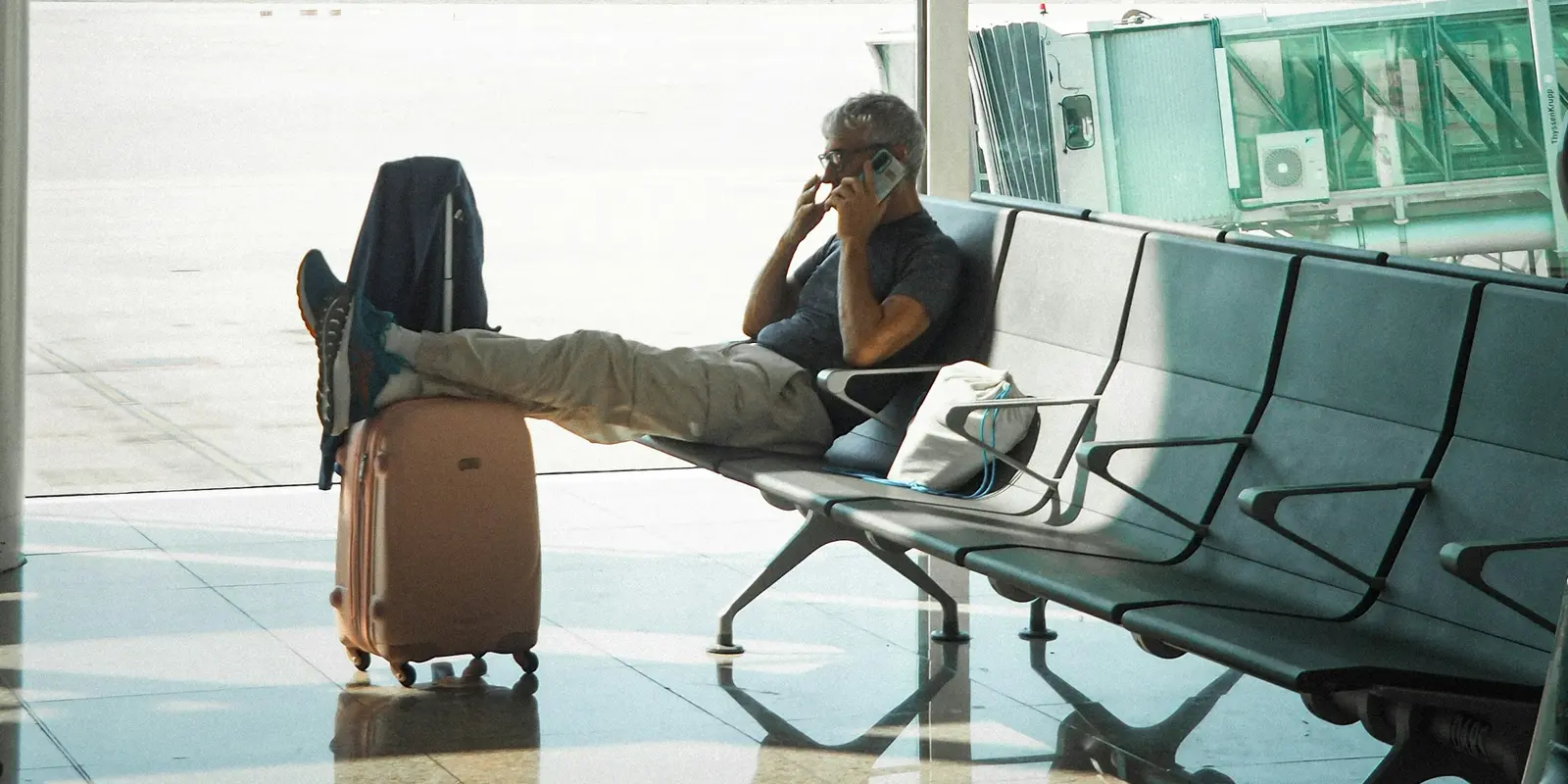 Mantener una segunda eSIM instalada como respaldo Viajero consultando su teléfono en una sala de espera de aeropuerto