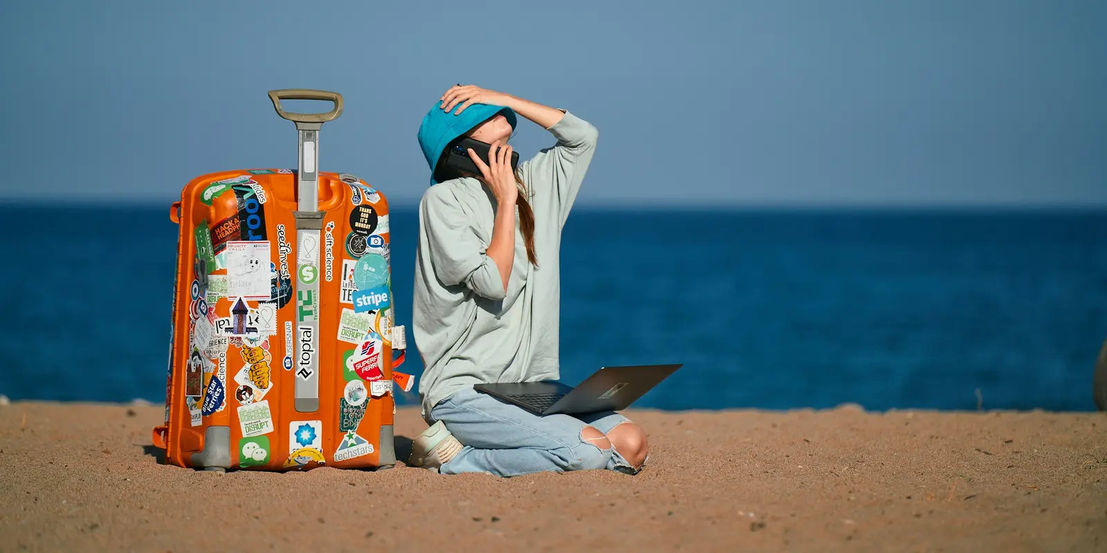 Traveler working on a laptop with a suitcase nearby