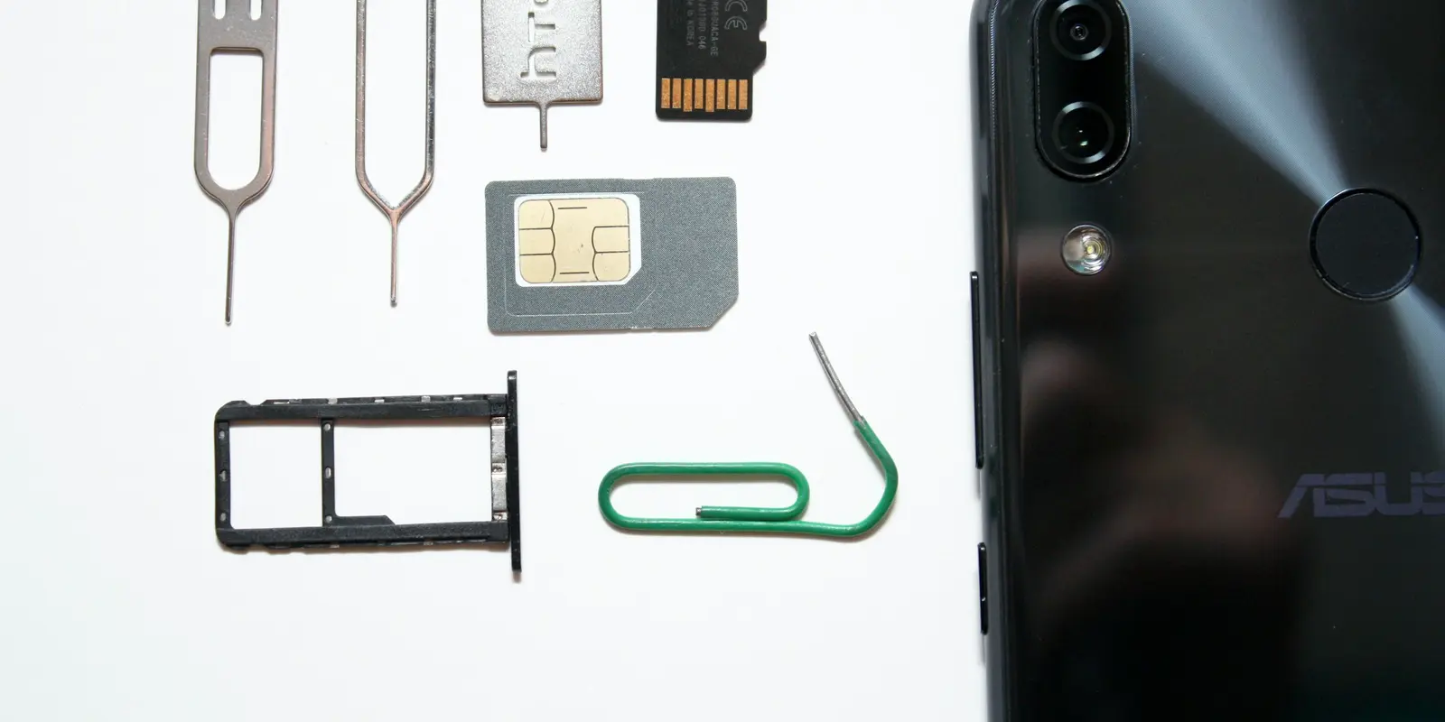 A hand holding a smartphone with a SIM card, illustrating the phone-settings side of an eSIM connectivity fix