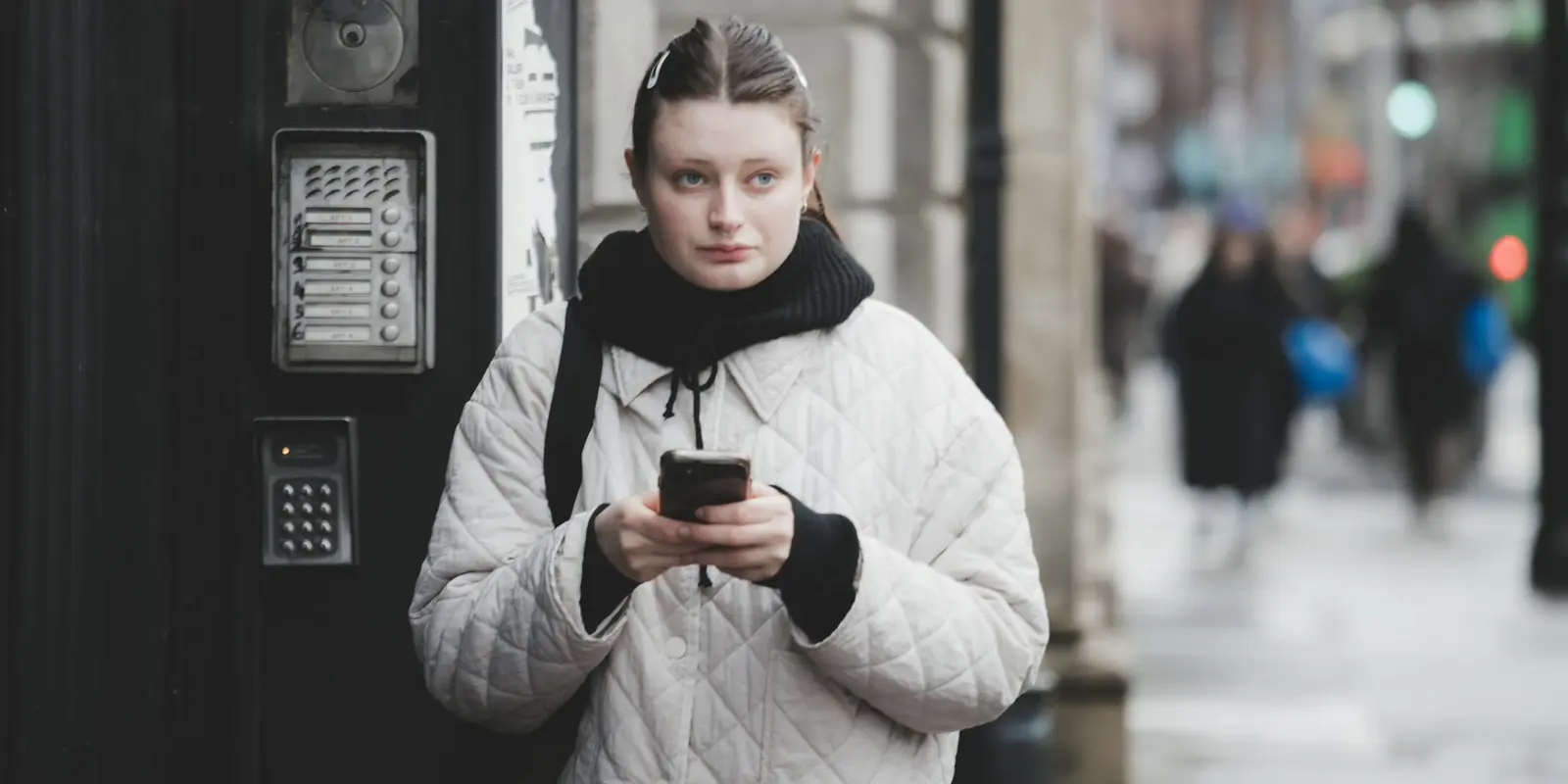 Traveler holding a smartphone outdoors with a city street in the background