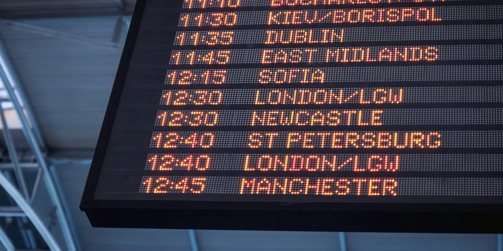 Traveler checking a flight departures board with a phone in hand