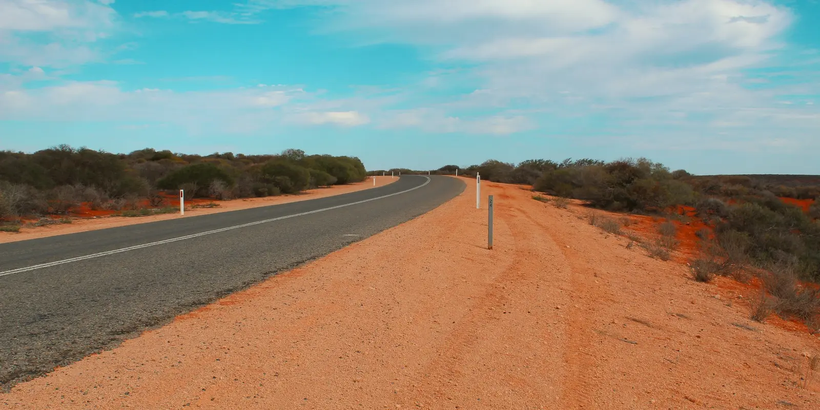 The kind of remote stretch where ordinary mobile coverage runs out Empty straight road stretching through the Australian outback desert