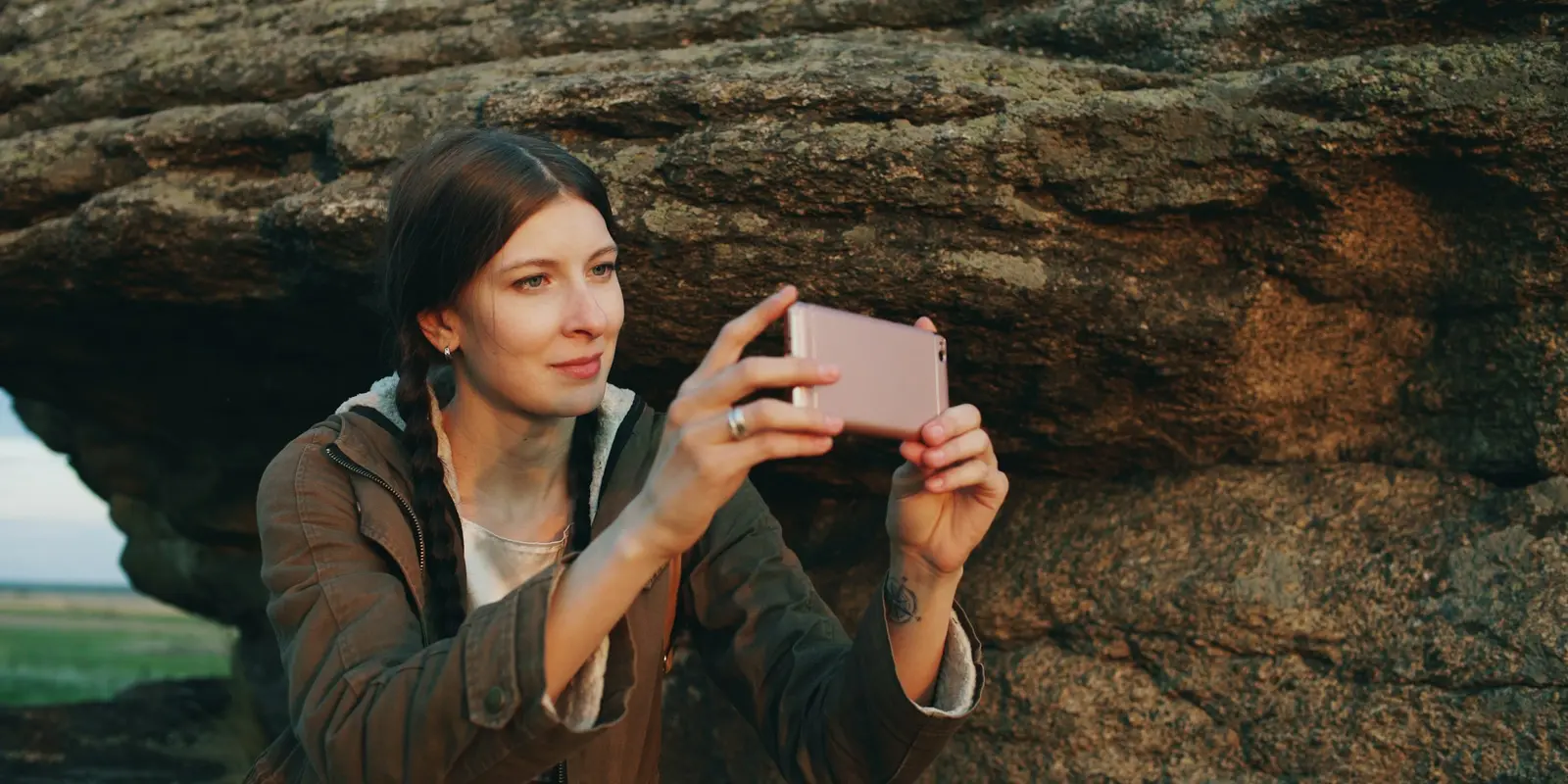 The hybrid strategy: eSIM for the first two weeks, local SIM after Backpacker photographing a rock formation landscape with a smartphone