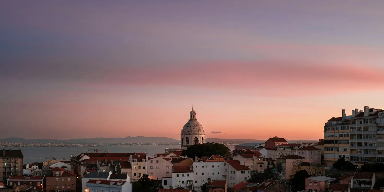 Sonnenuntergang über Lissabon — ein Ausblick, den man genießen kann, ohne sich um das genutzte Netzwerk zu sorgen Lissabons Skyline leuchtet bei Sonnenuntergang, gesehen von einem der Miradouros der Stadt