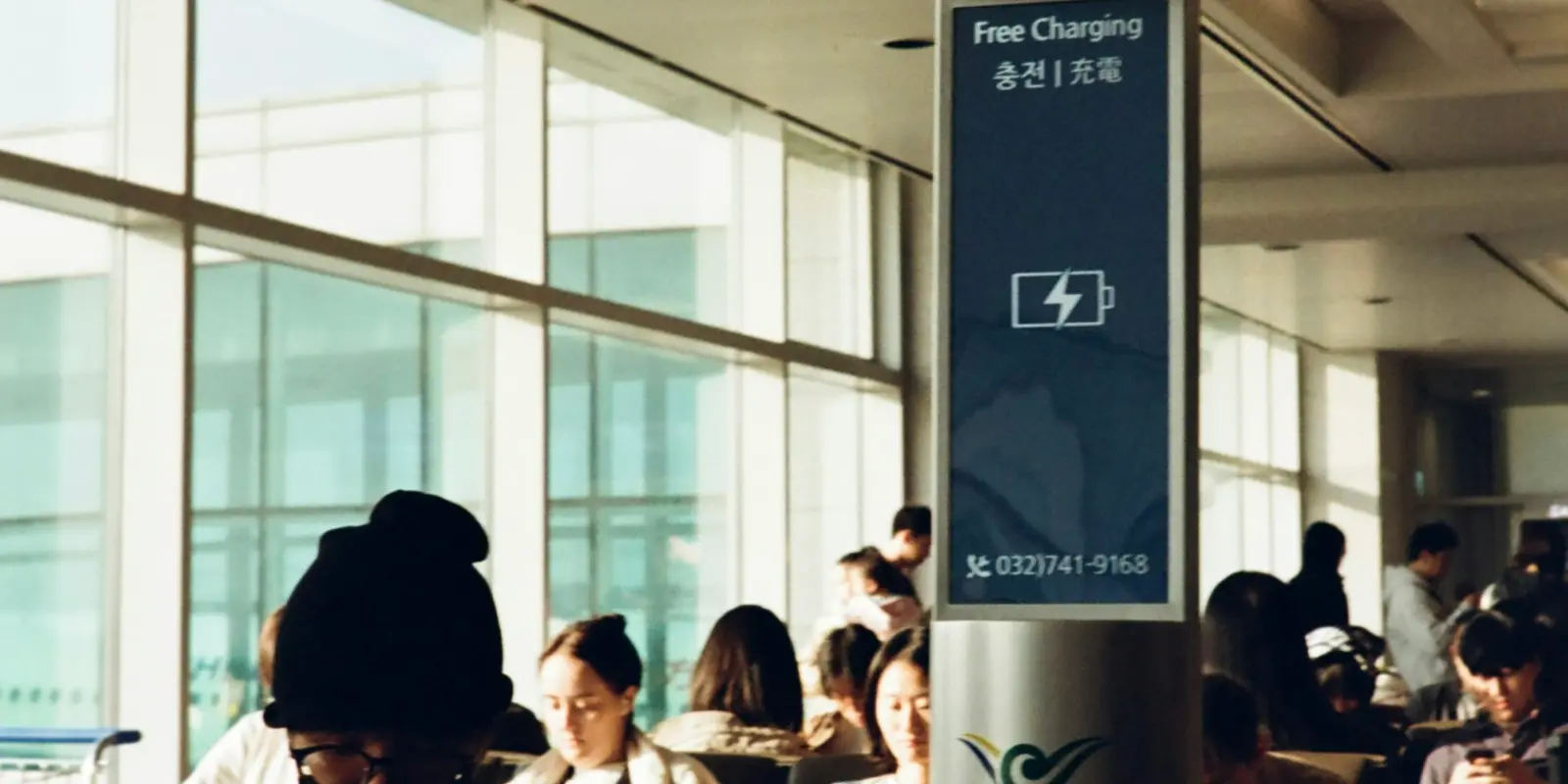 Passengers charging phones at a device-charging station in Incheon International Airport