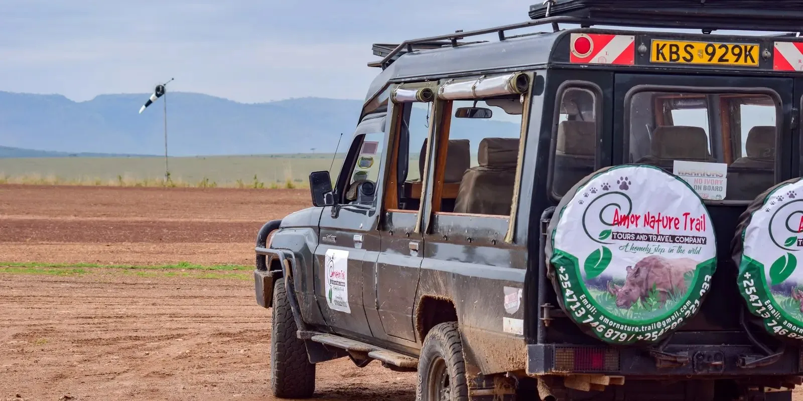 Un rendez-vous écrit reste utile quand le réseau disparaît sur une route de safari. Véhicule de safari sur une route en terre au Kenya