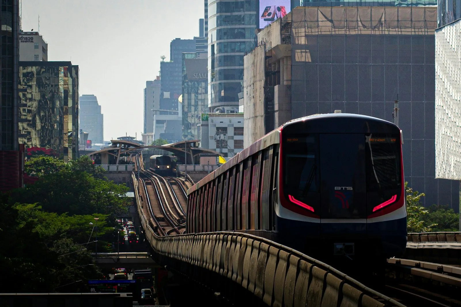 Train running through Bangkok beside city buildings