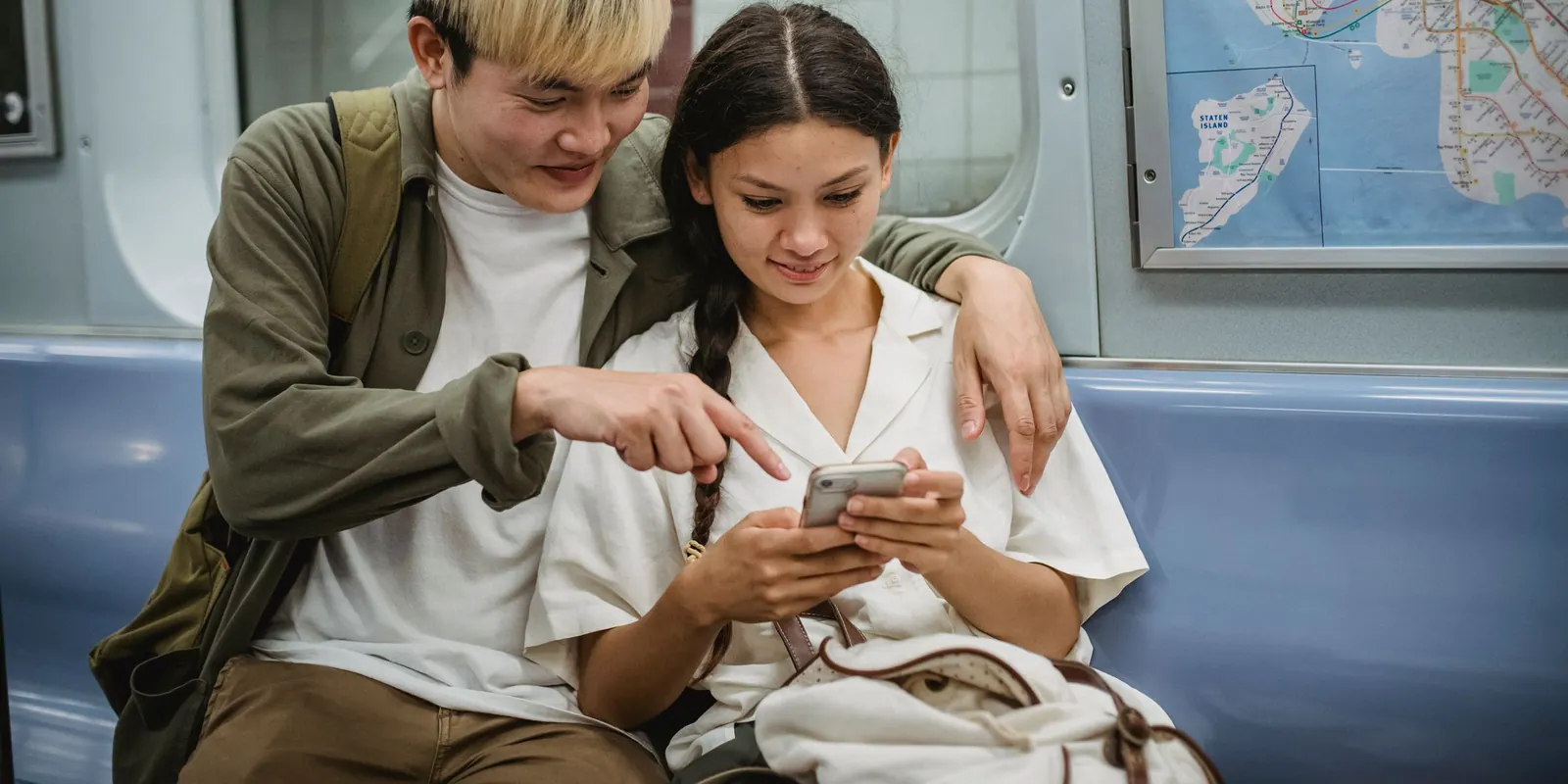 Zwei Reisende schauen gemeinsam auf ein Smartphone im Zug