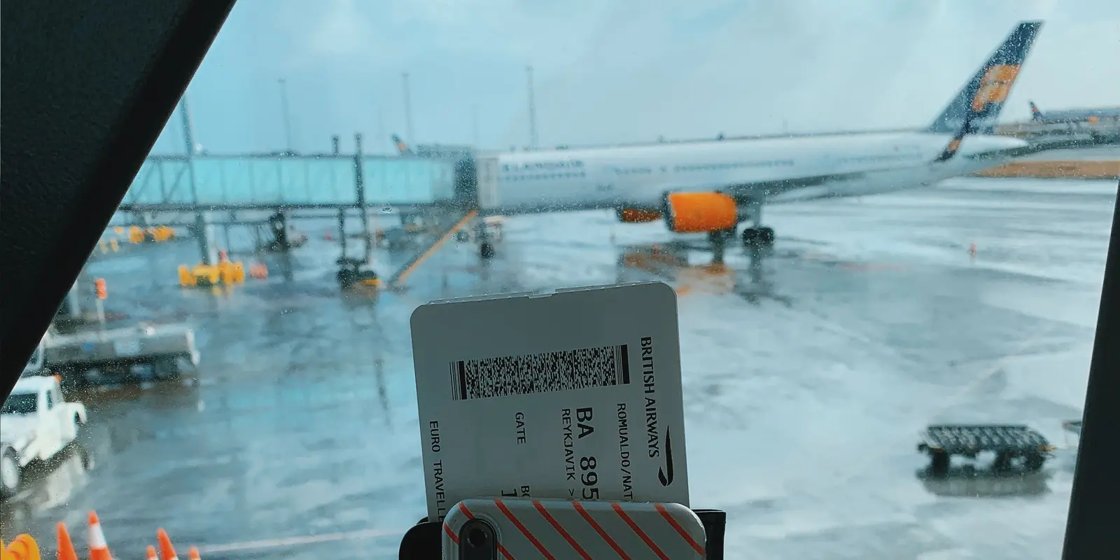 Eine reisende Person hält Smartphone und Bordkarte an einem Terminalfenster