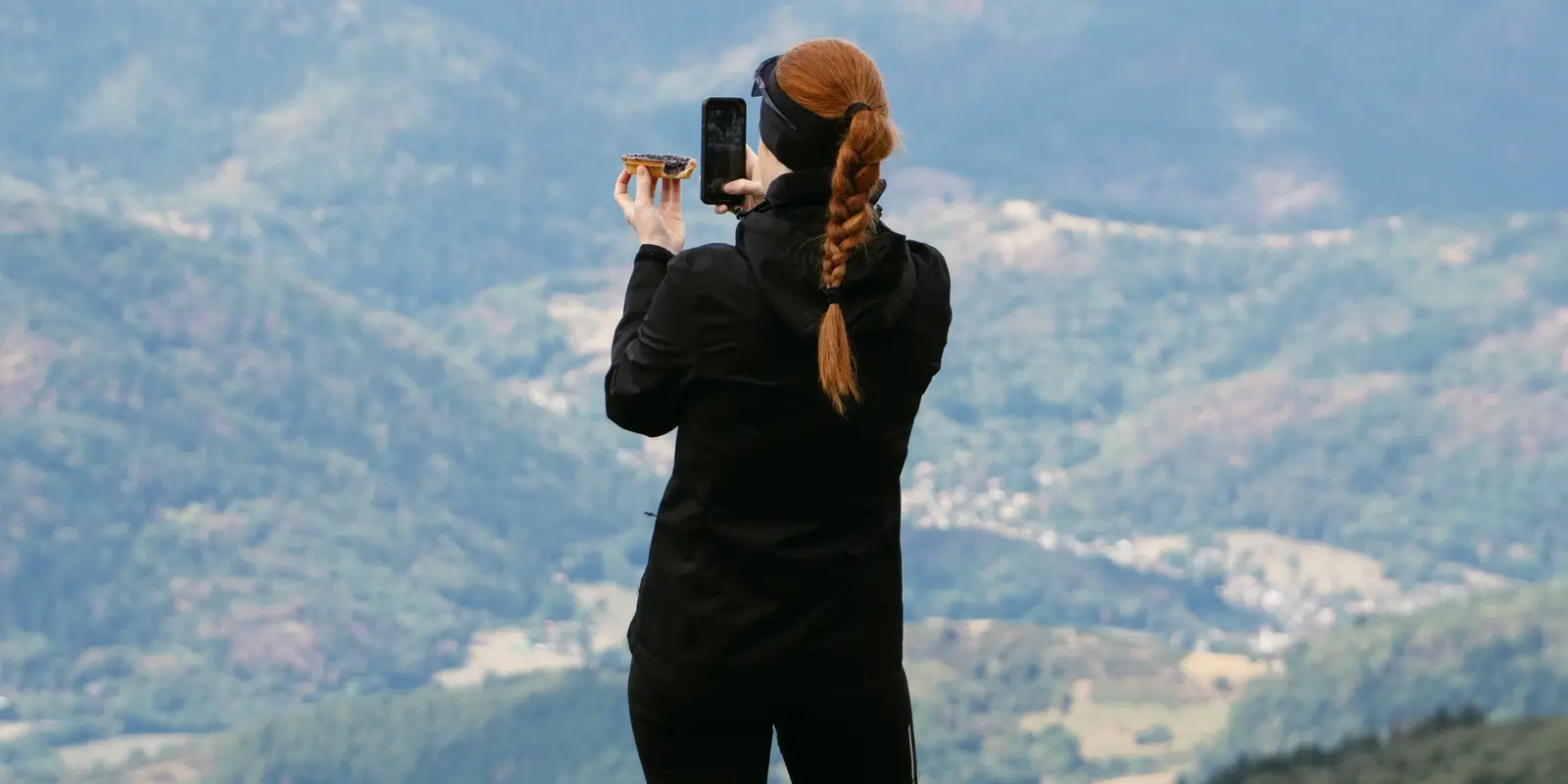 Eine Wanderin fotografiert mit ihrem Smartphone eine Berglandschaft