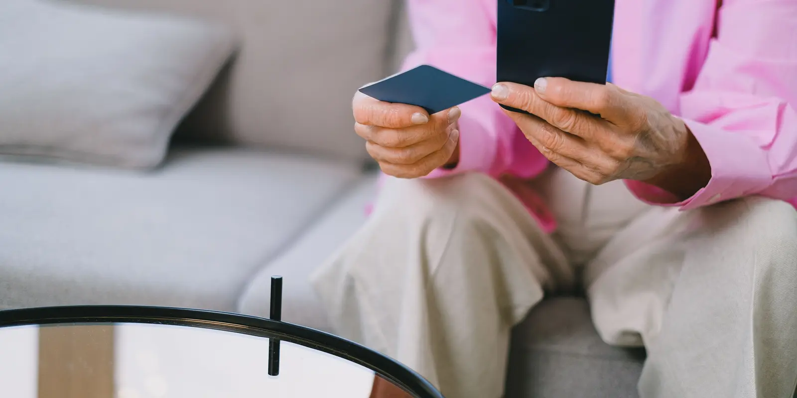 Eine ältere Person bezahlt mit Smartphone und Bankkarte online