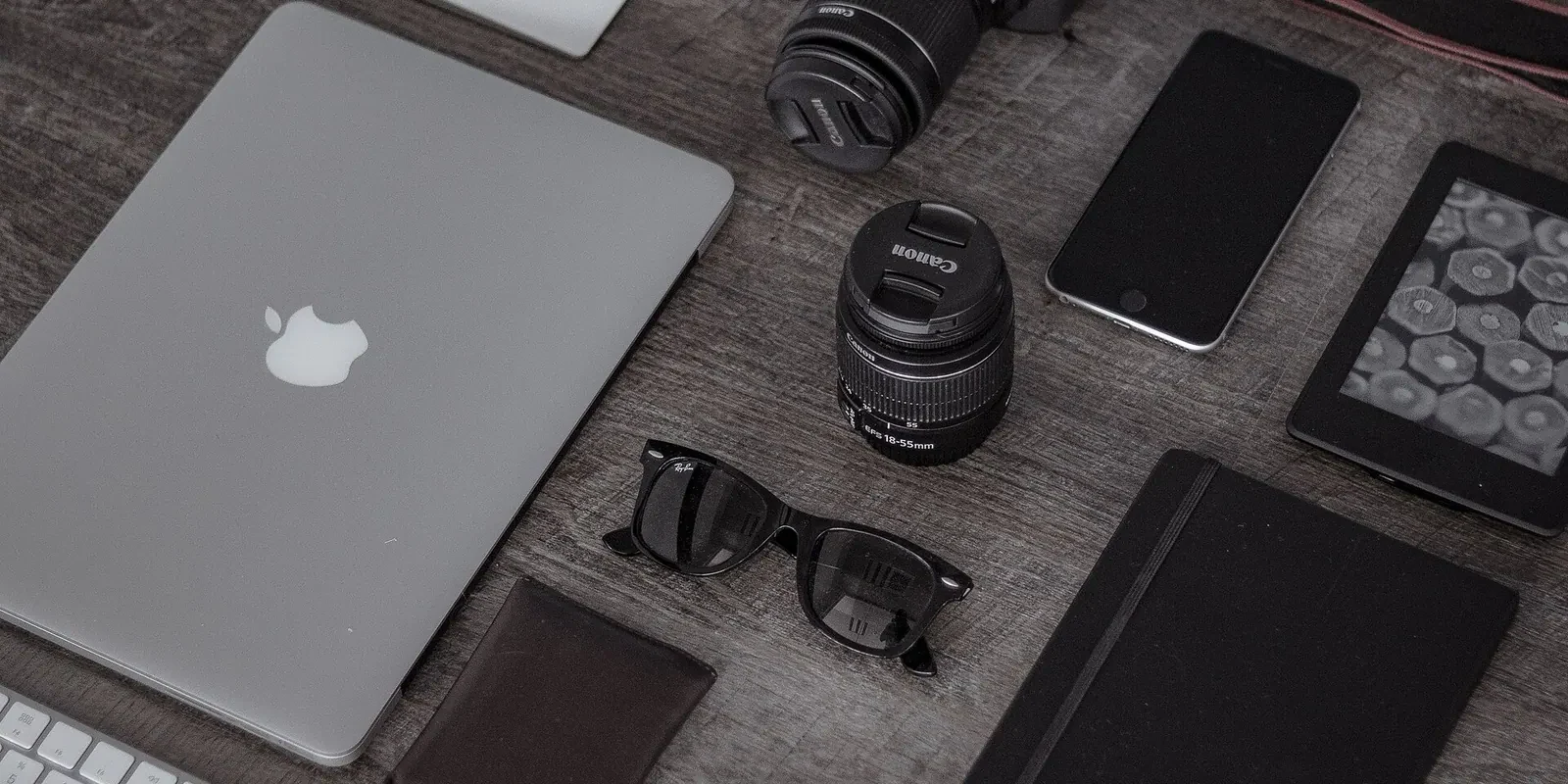 Un ordinateur portable, un smartphone, un appareil photo et des accessoires sur une table sombre.